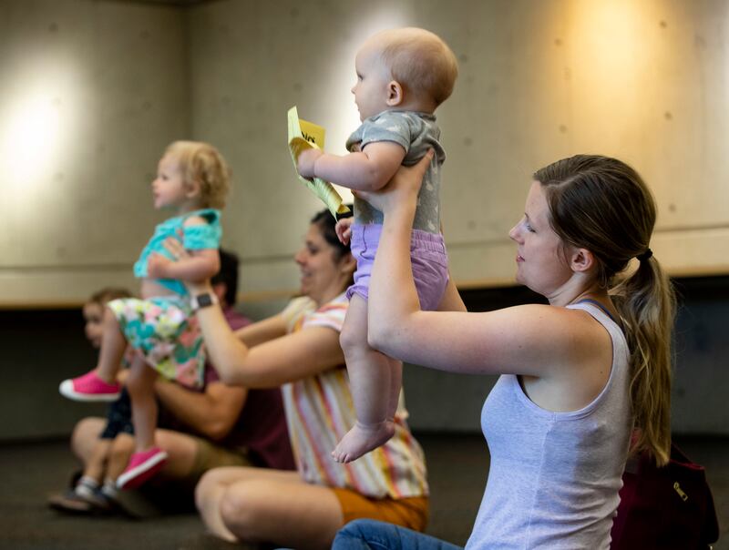 Elyse Stoedter, holds her 10-month-old daughter Sophia, as older children dance to a song during storytime at the Anderson-Foothill Library in Salt Lake City on Wednesday, June 19, 2019.