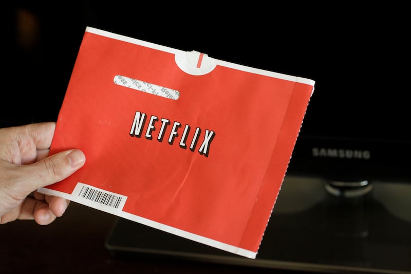 Customer holds The famous Netflix DVD red envelop.