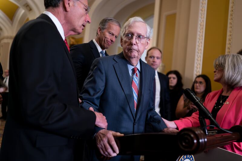 Senate Minority Leader Mitch McConnell, R-Ky., is helped by colleagues after he froze at the microphones on July 26, 2023.