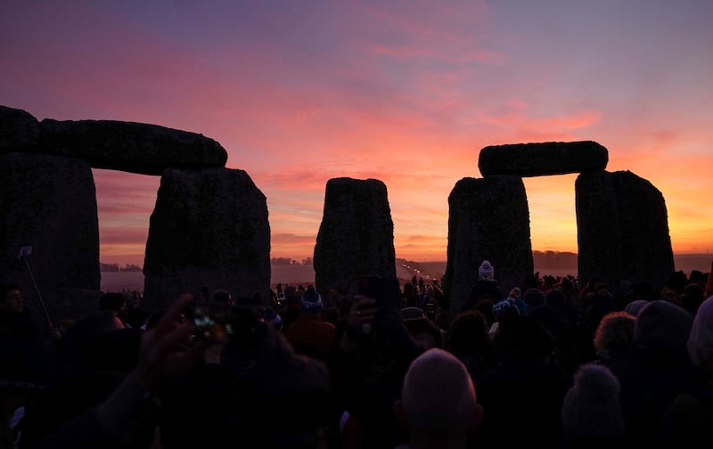 The sun begins to rise as people gather to take part in the winter solstice celebrations at Stonehenge monument, Dec. 22, 2021.