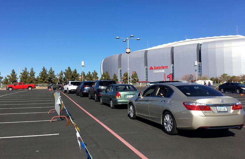 In this Jan. 11, 2021 fie photo drivers wait in line to get the COVID-19 vaccine in the parking lot of the State Farm Stadium in Glendale, Ariz. Arizona officials, who have pressed for more COVID-19 vaccines, got a chance to show the White House how quickly they could put them to use.
