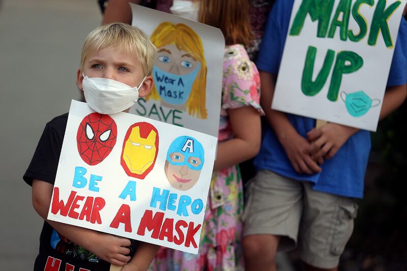 David Phillips holds a sign in support of school mask mandates.