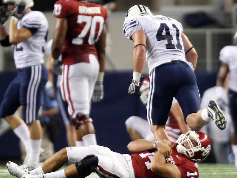 Oklahoma QB Sam Bradford rolls over in pain after being hit and dropped by BYU’s Coleby Clawson at Cowboys Stadium.