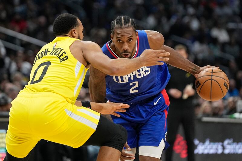 Los Angeles Clippers forward Kawhi Leonard, wearing blue, drives by Utah Jazz guard Talen Horton-Tucker during the second half of an NBA basketball game Monday, Nov. 21, 2022, in Los Angeles.