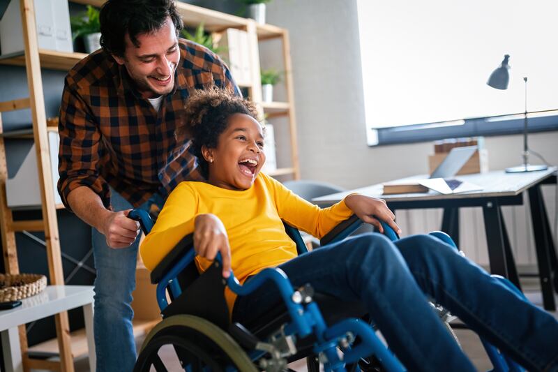 A man helps a young women in a wheelchair.