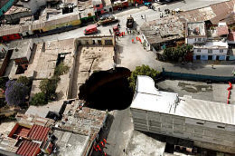A sinkhole swallowed several homes early Friday in Guatemala City. Two teens were killed, and their father is missing.