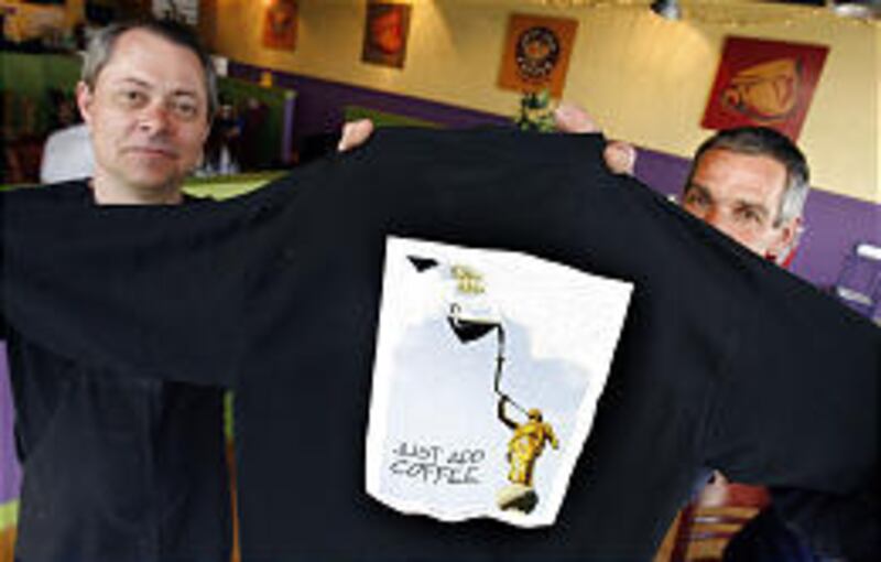 Ed Beazer, left, and Van Lidell, owners of Just Add Coffee, display a T-shirt Thursday that the LDS Church has asked them to stop selling, along with a request to remove Moroni from their advertising.