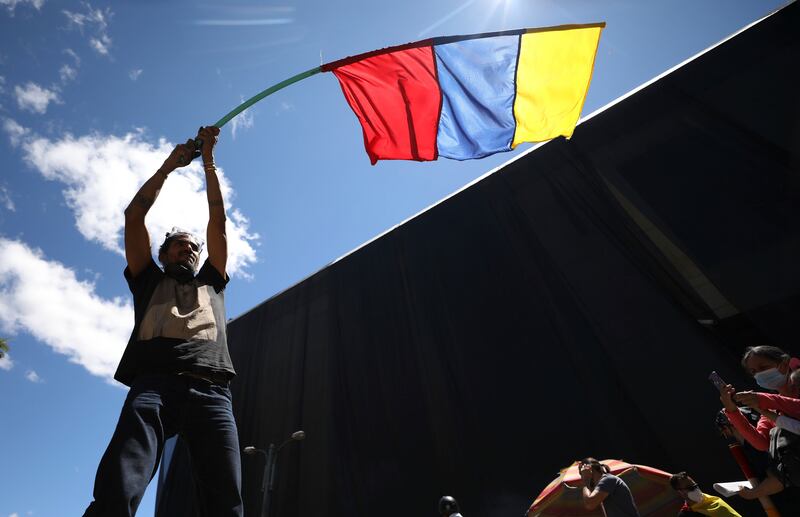 A man waves a banner representing Colombia’s national colors.