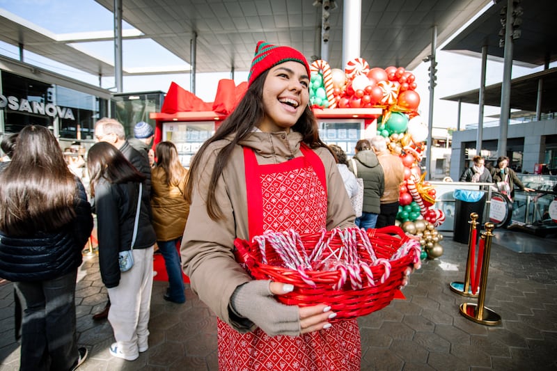 A volunteer at the Giving Machines in Barcelona, Spain, joyfully hands out candy to those visiting the new machines on Nov. 28, 2025.