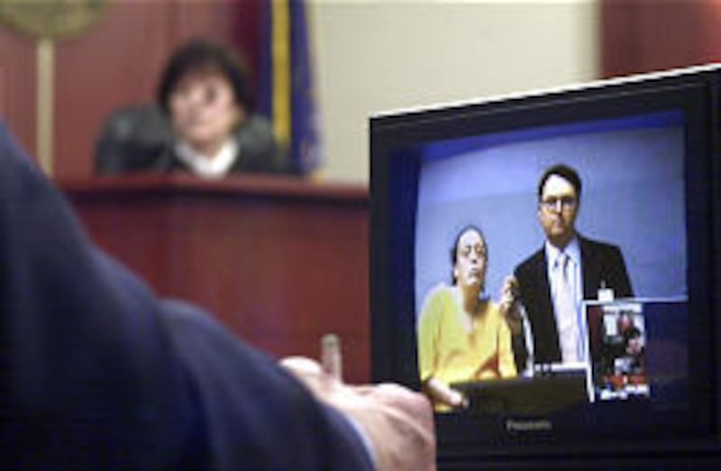 Melissa Ann Rowland and public defender Mark Helm appear in court before Judge Sandra Peuler, rear, via closed circuit television from jail. She pleaded not guilty.