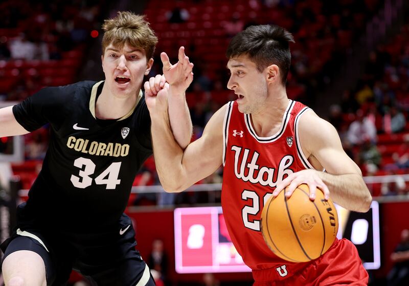 Utah Utes guard Lazar Stefanovic (wearing red) works to get away from Colorado Buffaloes center Lawson Lovering (wearing black).
