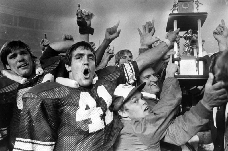 Glen Redd (41) and coach LaVell Edwards lead victory celebration around Holiday Bowl trophy after stunning victory. Dec. 20, 1980. BYU-46, SMU-45.