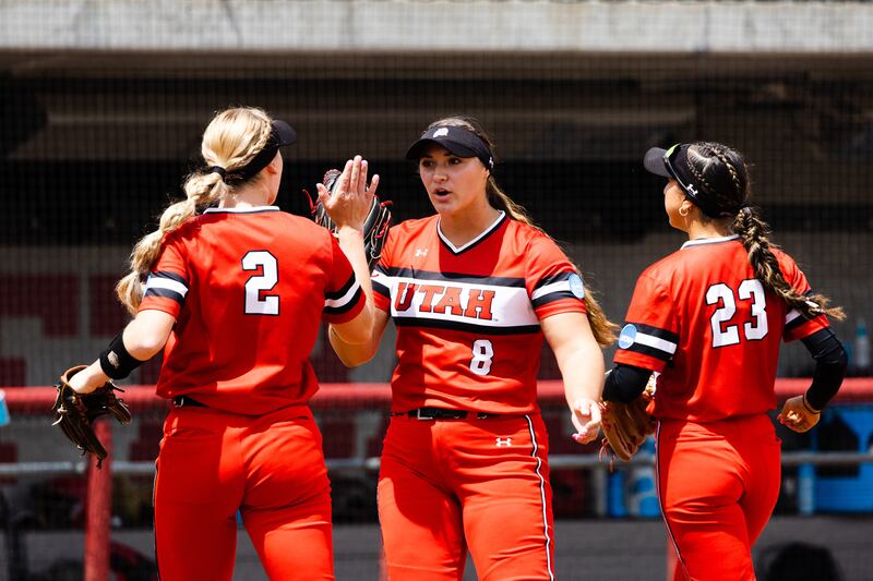 Utah pitcher Mariah Lopez (wearing red) high-fives teammates Utah infielder Ellessa Bonstrom and Utah infielder Aliya Belarde