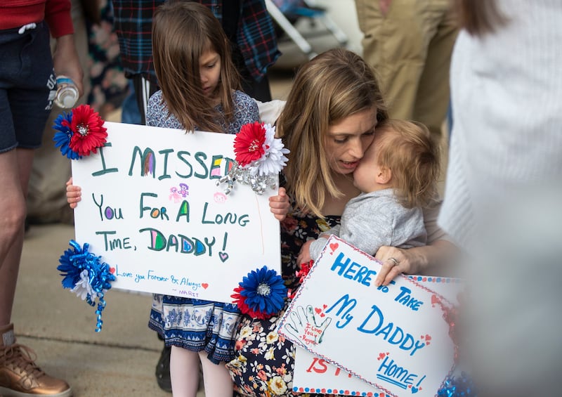 Jesi Davila holds daughter, Marit, 5, and her son Rayner, 1, and holds a signs while waiting for her husband Roger to disembark from the plane that carried 128 warriors home from a seven-month deployment at Hill Air Force Base on Monday, April 29, 2019.