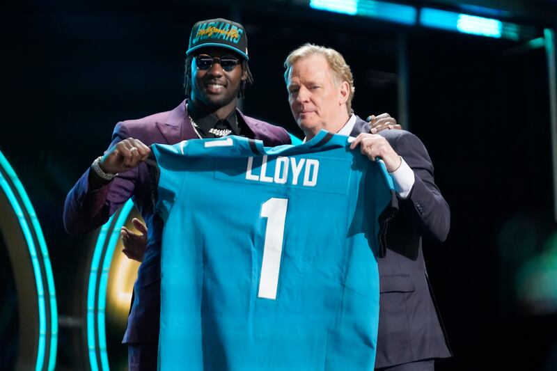 Utah linebacker Devin Lloyd, left, and NFL Commissioner Roger Goodell hold a team jersey afterLloyd was chosen by the Jacksonville Jaguars with the 27th pick at the 2022 NFL draft.