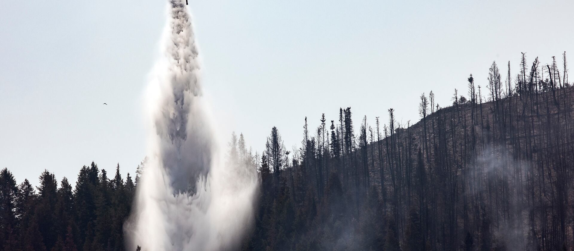 A helicopter drops water on hot spots as crews fight the Parleys Canyon Fire near Park City.