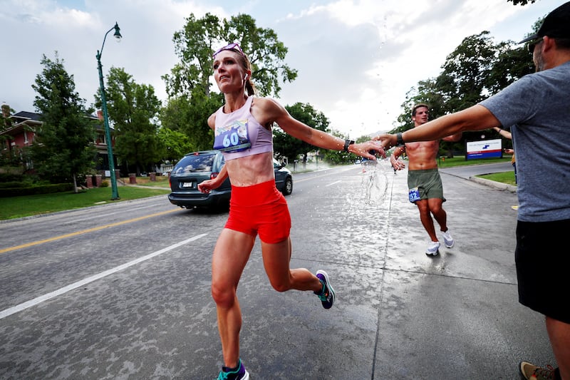 Bethany Brown drops a cup of water as she runs in the Deseret News Marathon in Salt Lake City.
