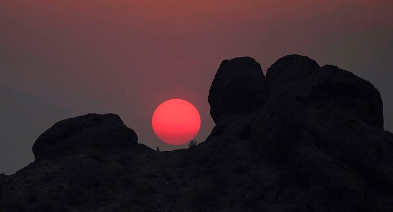 A hiker pauses as temperatures reached 115-degrees Tuesday, June 15, 2021, in Phoenix.