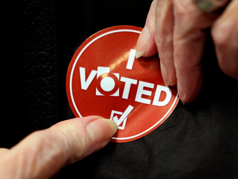 A voter applies her “I voted” sticker at the Salt Lake County Government Center on Nov. 21, 2023.