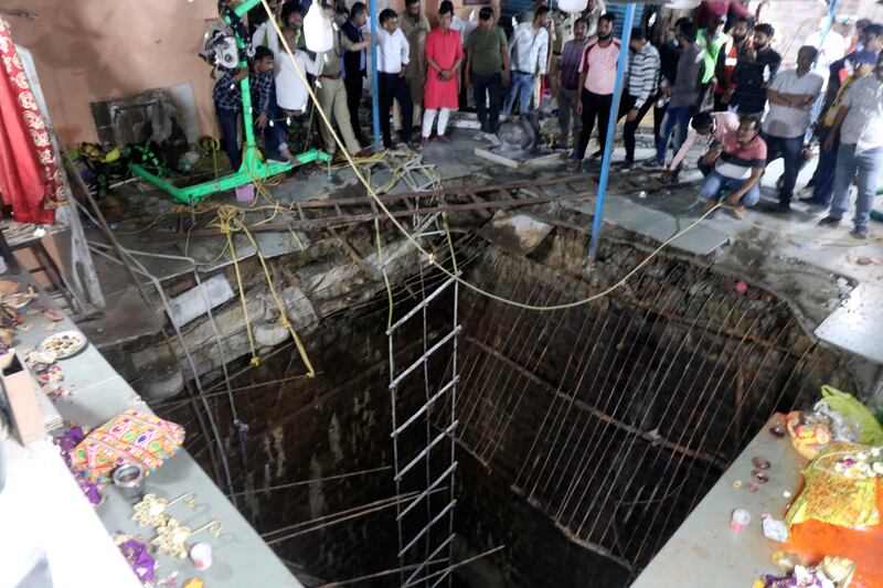 People stand around a structure built over an old temple well that collapsed Thursday as a large crowd of devotees gathered for the Ram Navami Hindu festival in Indore, India.