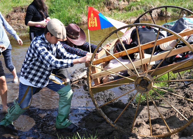 Latter-day Saint youth and leaders participate in trek, pushing a handcart through mud during the June 13 and 14, 2025, trek near Ulaanbatar, Mongolia.
