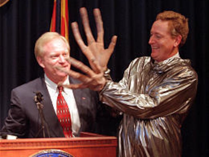 Then-Arizona Gov. Fife Symington jokes with aide Jay Heiler, right, on June 19, 1997, after Symington had introduced his costumed aide as being a captured alien and then unmasking him.