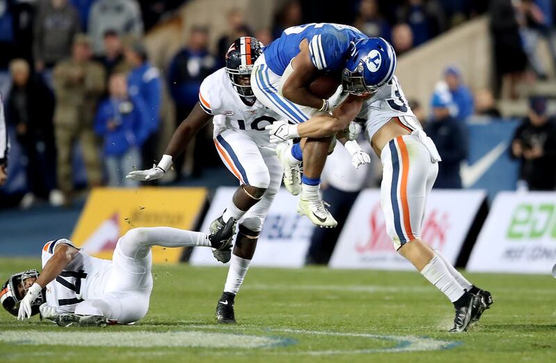 BYU Cougars running back Tyler Allgeier (25) is hit hard by Virginia Cavaliers linebacker West Weeks (33) on Oct. 30, 2021. How will the College Football Playoff Committee treat BYU?