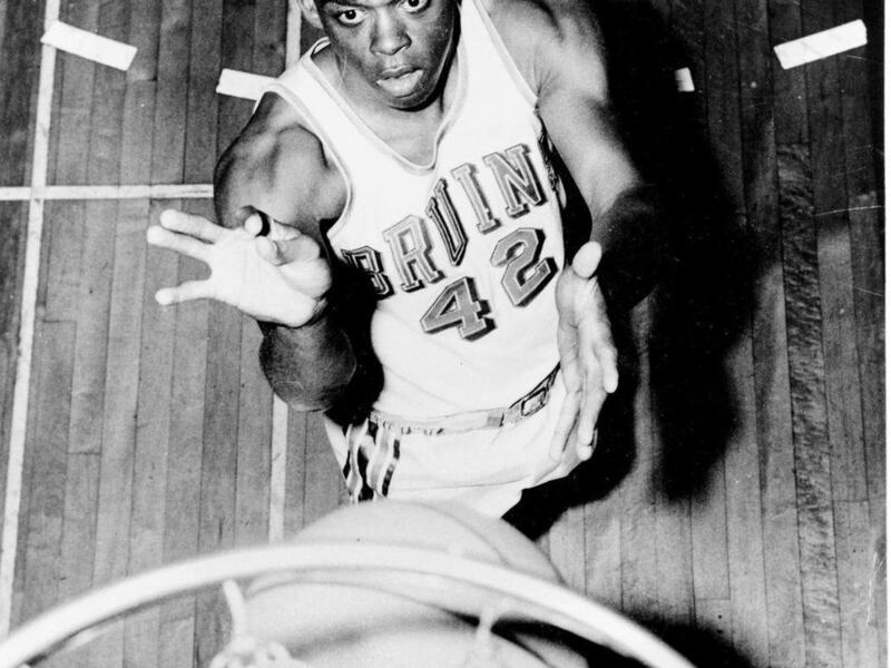 FILE - In this 1962 file photo, UCLA basketball guard Walt Hazzard, poses under a net. Hazzard, the former UCLA and NBA star who played on the Bruins' first NCAA championship basketball team in 1964 and later coached the team for four seasons in the 1980