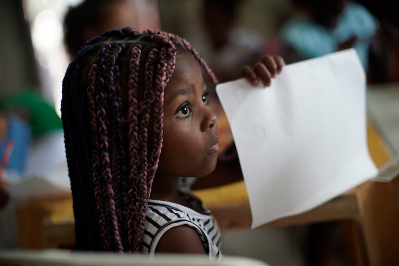 A girl shows her work to the teacher during a class at community library amid the new coronavirus pandemic at the Morro do Salgueiro favela of Rio de Janeiro, Brazil, Thursday, Aug. 27, 2020.