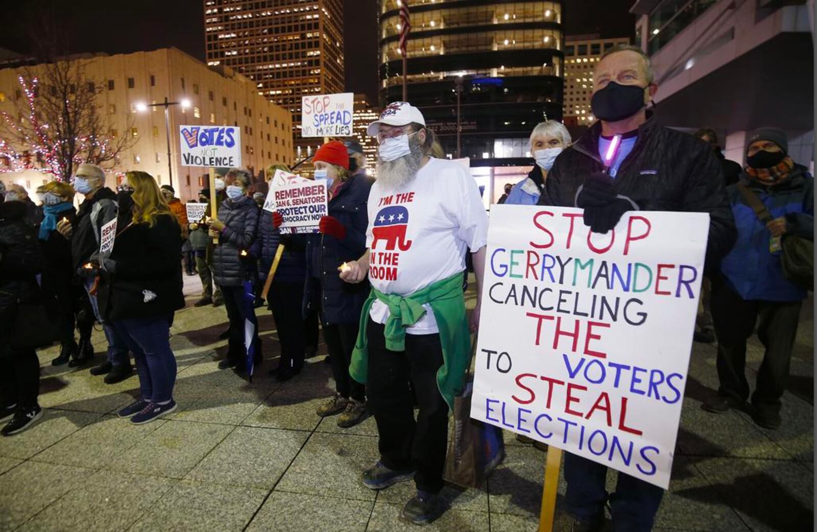 Participants display signs during a vigil held on the first anniversary of the Jan. 6, 2021, insurrection in Salt Lake City.