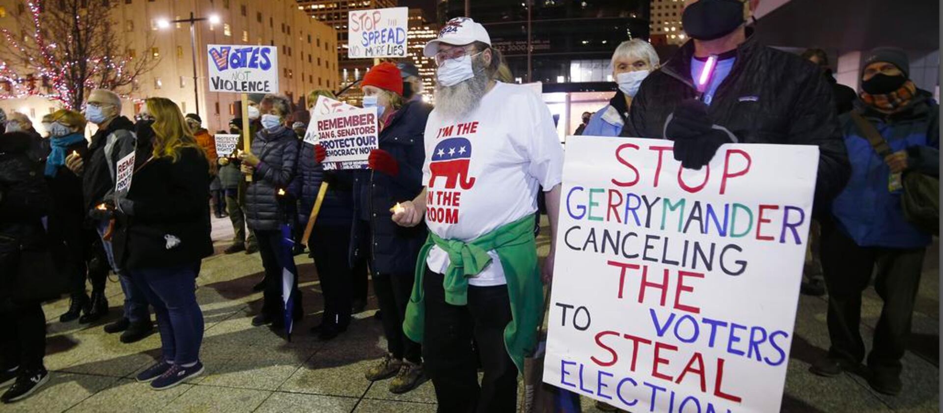 Participants display signs during a vigil held on the first anniversary of the Jan. 6, 2021, insurrection in Salt Lake City.