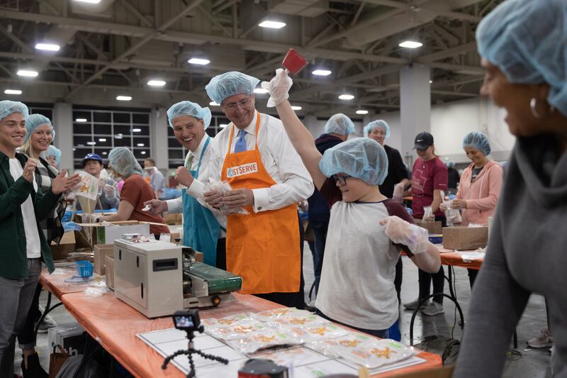 Volunteers cheer as a young boy rings the bell to celebrate another packaged box of meals at the Silicon Slopes Serves event.