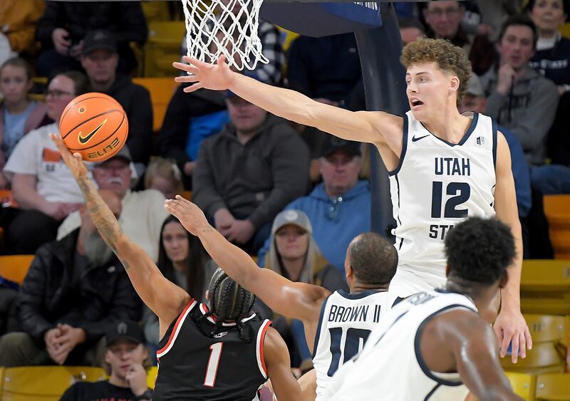 Northwest Nazarene guard Tru Allen (1) shoots as Utah State guard Mason Falslev (12) defends during the first half of an NCAA college basketball game Saturday, Dec. 9, 2023, in Logan, Utah. (Eli Lucero/The Herald Journal via AP)