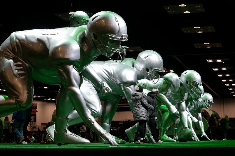 Fans stand by statues at Playoff Fan Central, Saturday, Jan. 8, 2022, in Indianapolis.