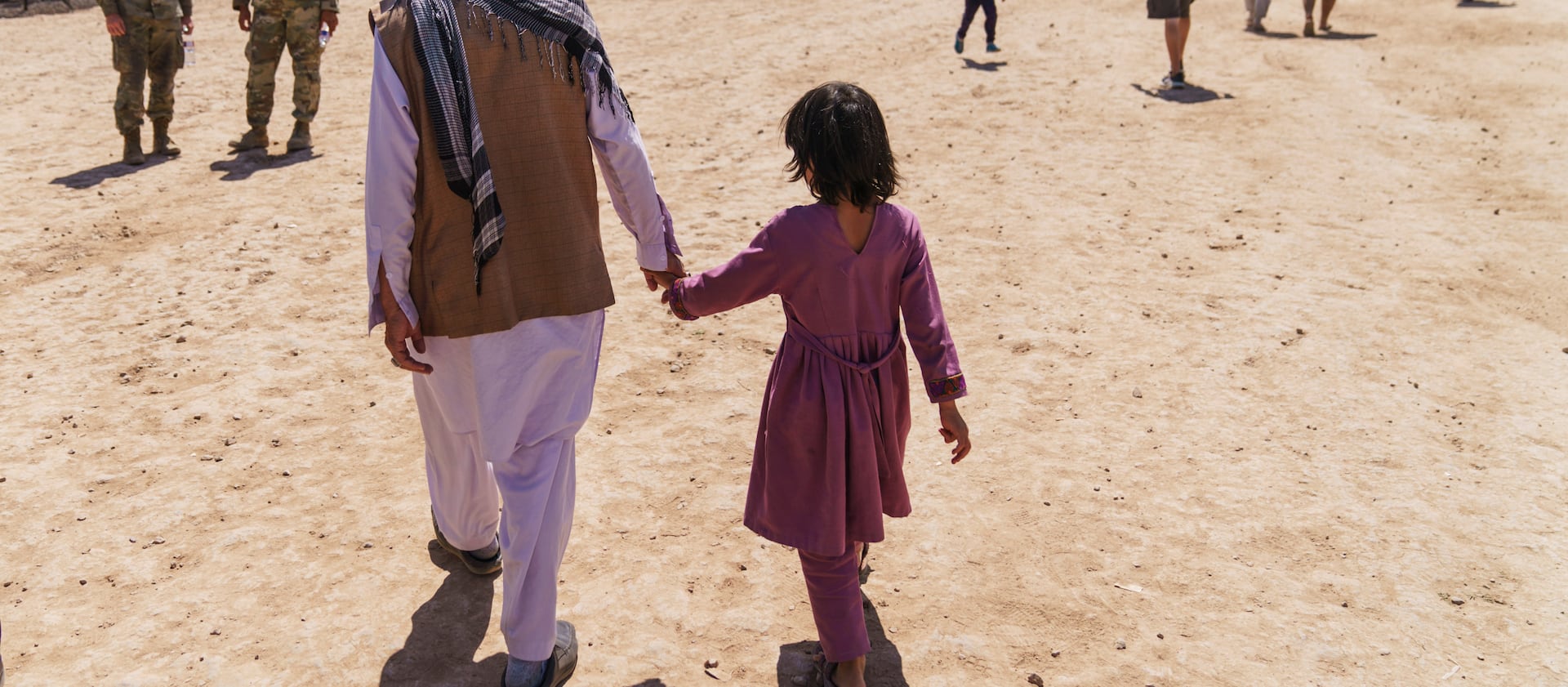 A man walks with a child through Fort Bliss’ Doña Ana Village where Afghan refugees are being housed, in New Mexico.