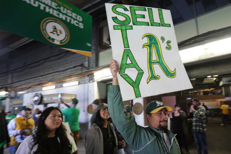 A fan holds a sign to protest the Oakland Athletics’ planned move to Las Vegas in June 2023.