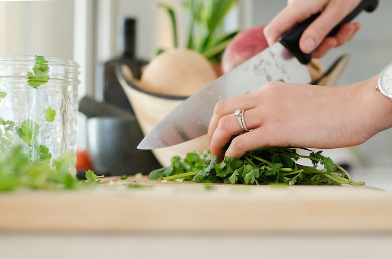 A woman chops cilantro in her kitchen.