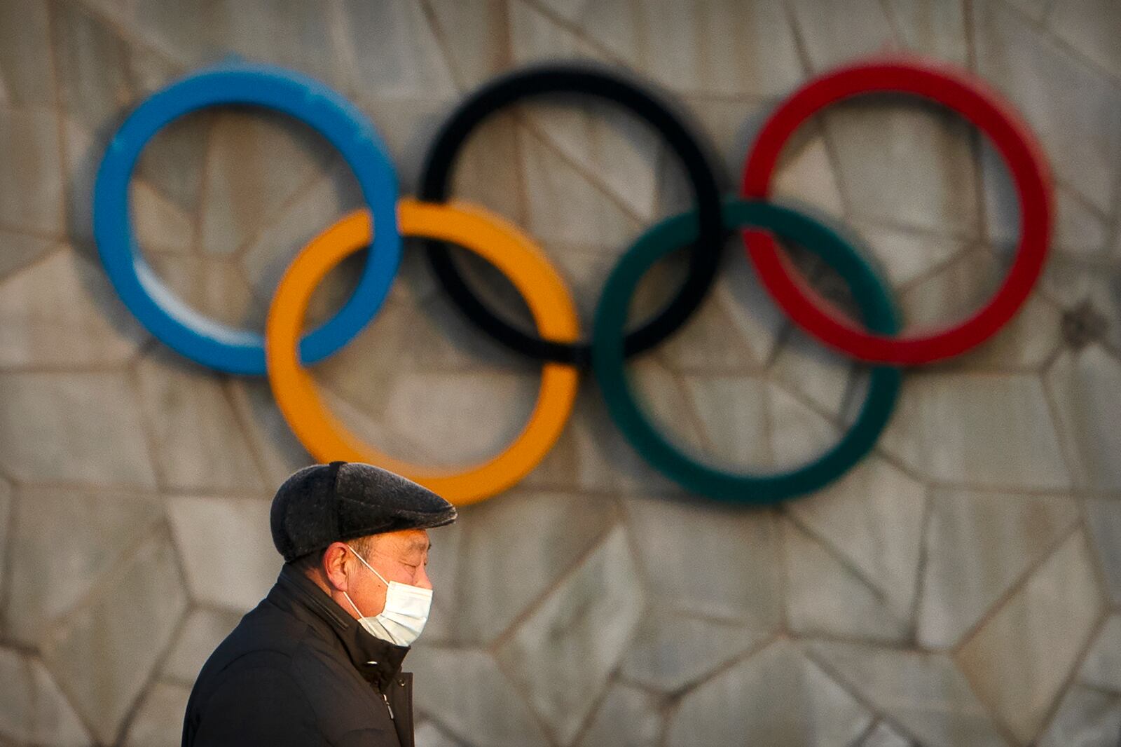 A man walks past the Olympic rings on the National Stadium, which will be a venue for the 2022 Winter Olympics in Beijing.
