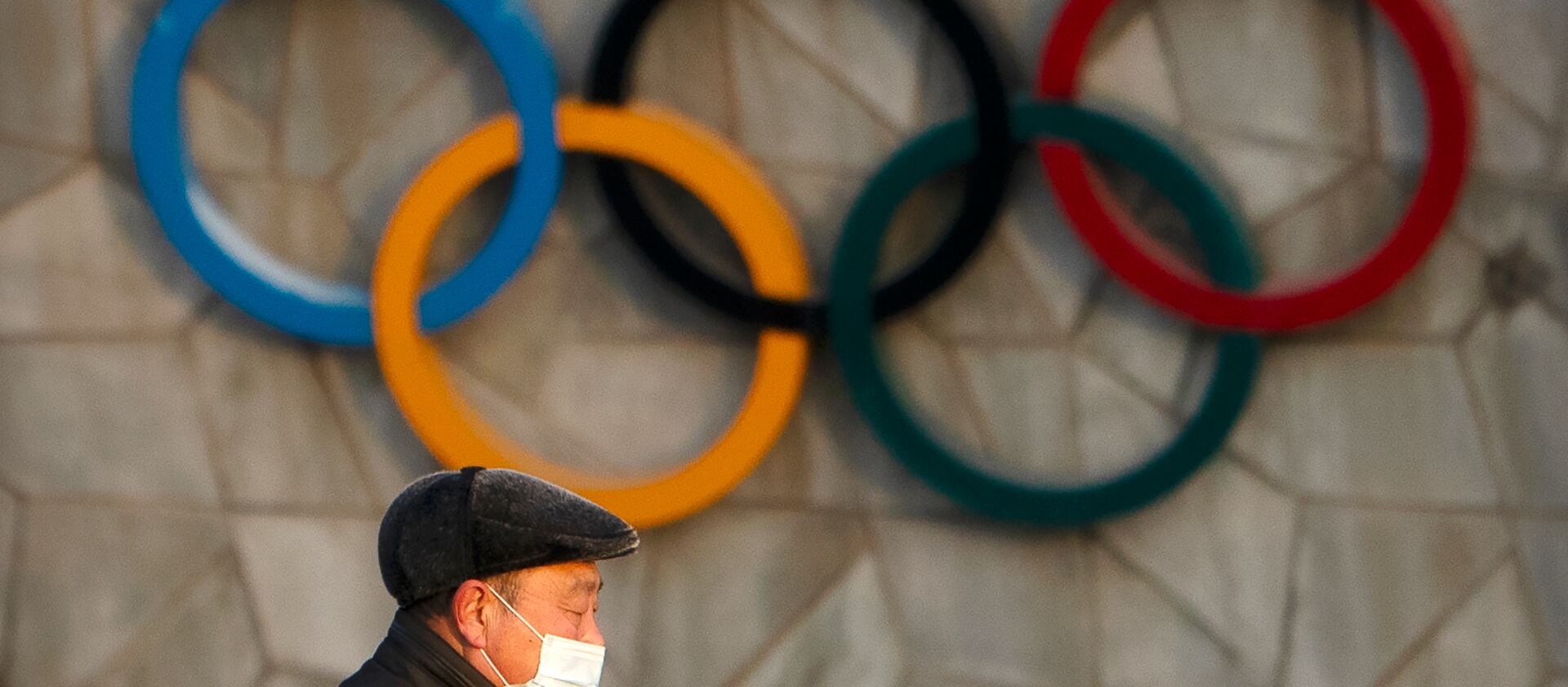 A man walks past the Olympic rings on the National Stadium, which will be a venue for the 2022 Winter Olympics in Beijing.
