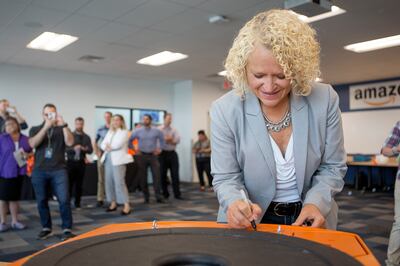Salt Lake City Mayor Jackie Biskupski signs a robot that will be used at Amazon's new Utah fulfillment center in Salt Lake City on Monday, Aug. 13, 2018. The 855,000-square-foot facility will employ over 1,500 full-time workers, shipping smaller items to