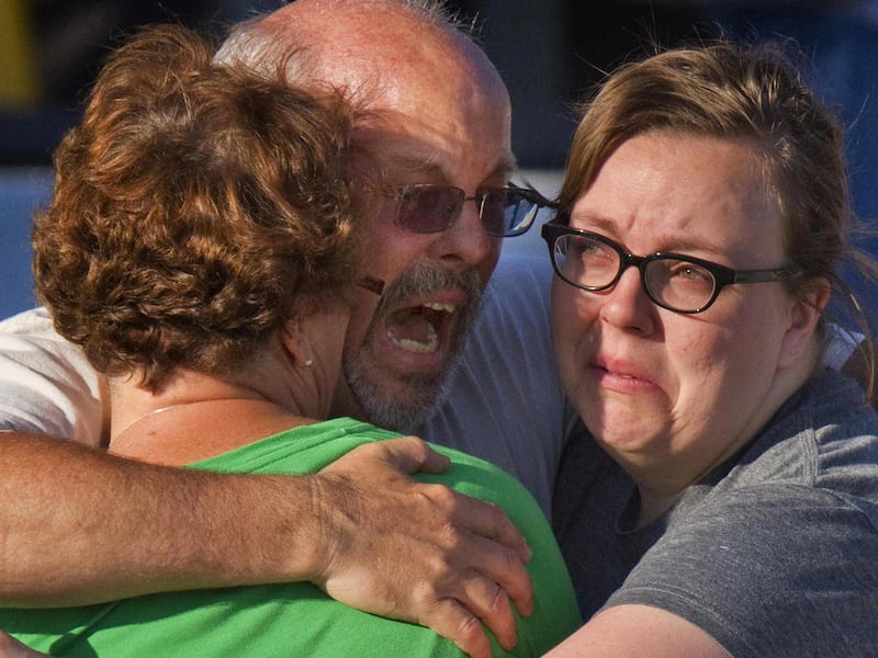 Tom Sullivan, center, embraces family members outside Gateway High School where he has been searching franticly for his son Alex Sullivan who celebrated his 27th birthday by going to see "The Dark Knight Rises," movie where a gunman opened fire Friday, Ju