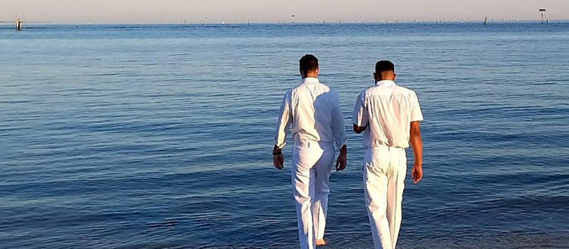 Elder Samuel Nagliati, a missionary for The Church of Jesus Christ of Latter-day Saints, left, walks into the Adriatic Sea with Lucky Ughulu to baptize him.
