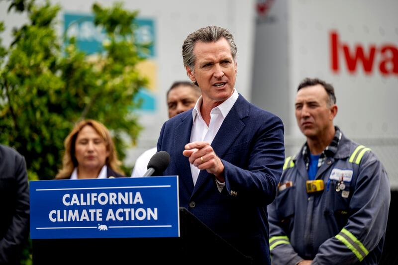 California Gov. Gavin Newsom stands behind a climate change sign and speaks during a news conference in Paramount, California.