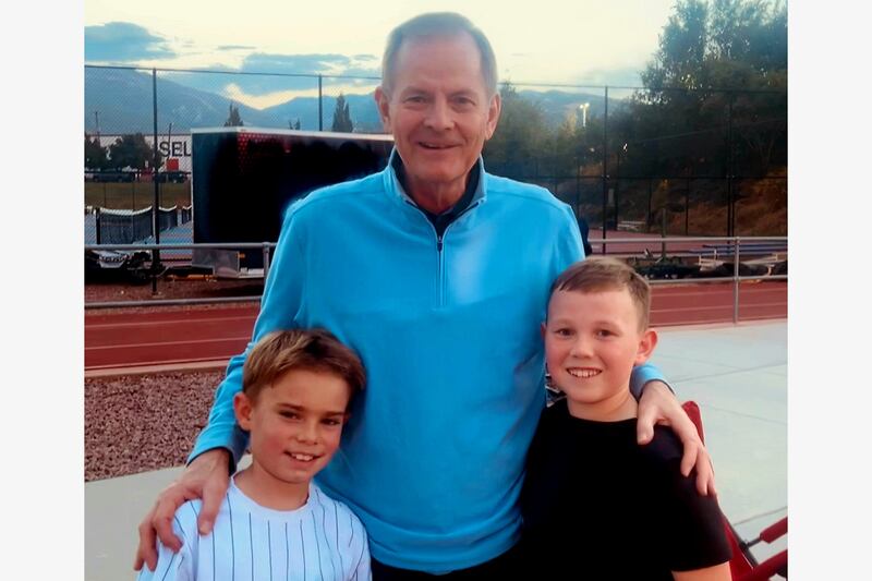 Elder Stevenson with two 9-year-old boys outside with a football stadium in the background.