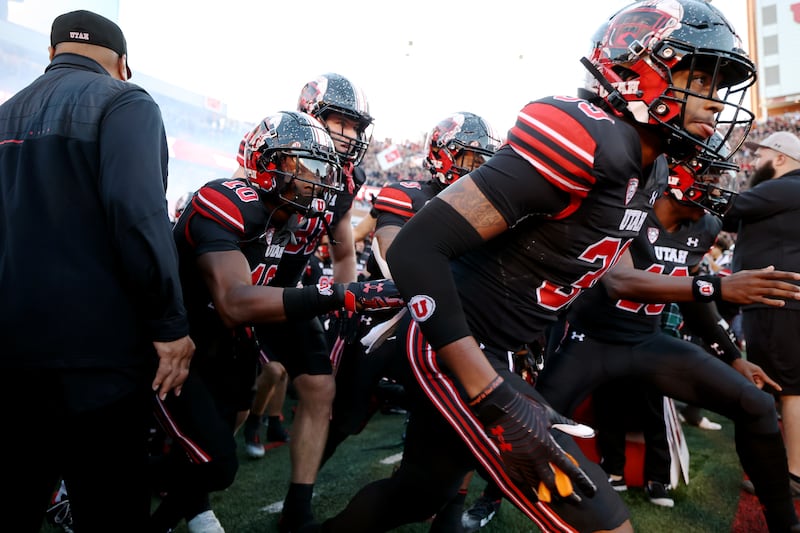 Utah players, wearing black, run out onto the field.