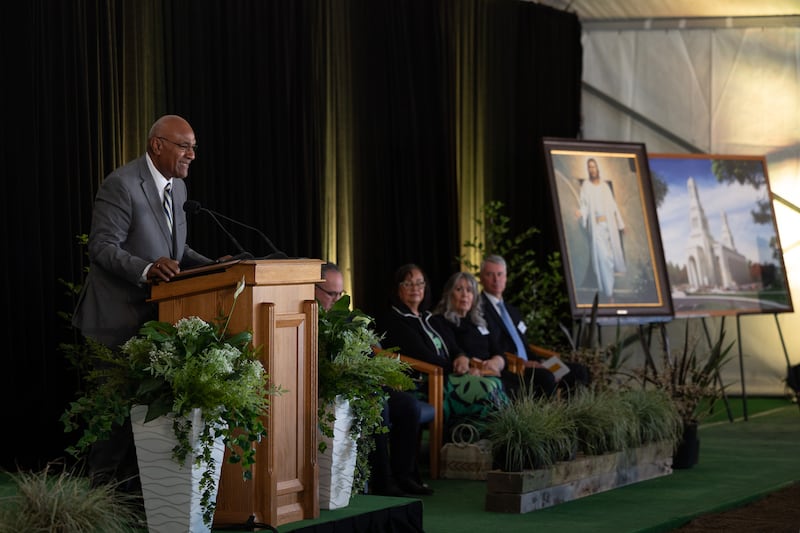 Elder Taniela B. Wakolo wearing a suit and speaking from a pulpit.