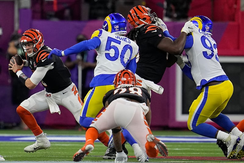 Cincinnati Bengals quarterback Joe Burrow, left, rolls out of the pocket against the Los Angeles Rams during the second half of Super Bowl 56.