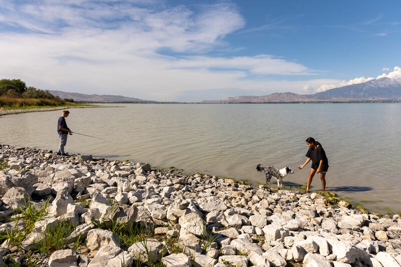 Joshua Larson fishes in Utah Lake while his girlfriend, Katelyn Molen, plays with their dog, Theo, on Monday, Aug. 22, 2022.