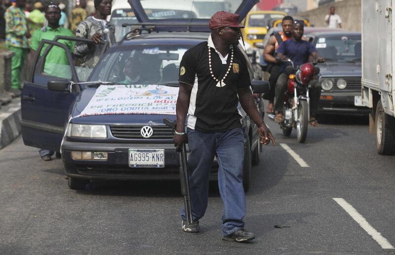 An unidentified member of  Oodua People's Congress militia walk with a gun on a  major street, during a protest against Boko haram in Lagos, Nigeria,Thursday, Dec. 8, 2011. A militia group from Nigeria's southwest walked through the streets of the commerc