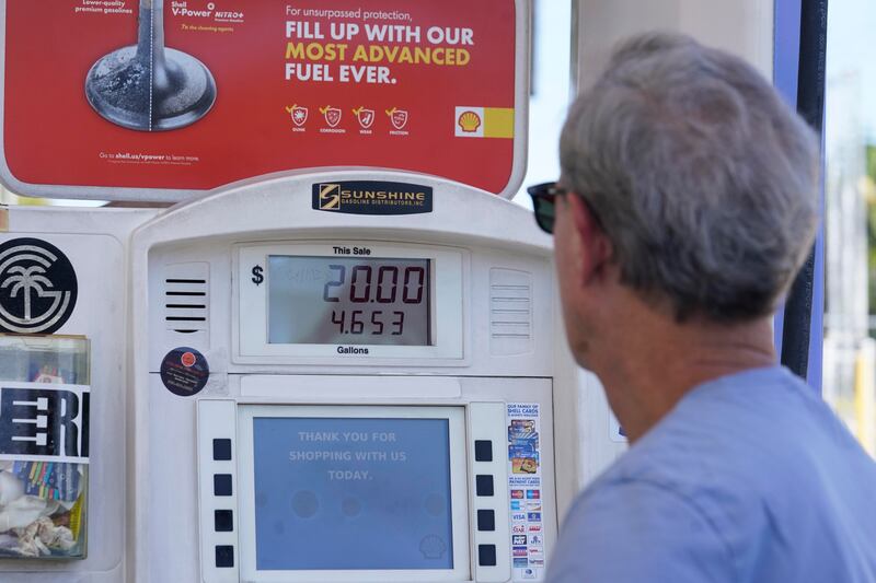 A customer is pictures pumping gas and staring at high prices.